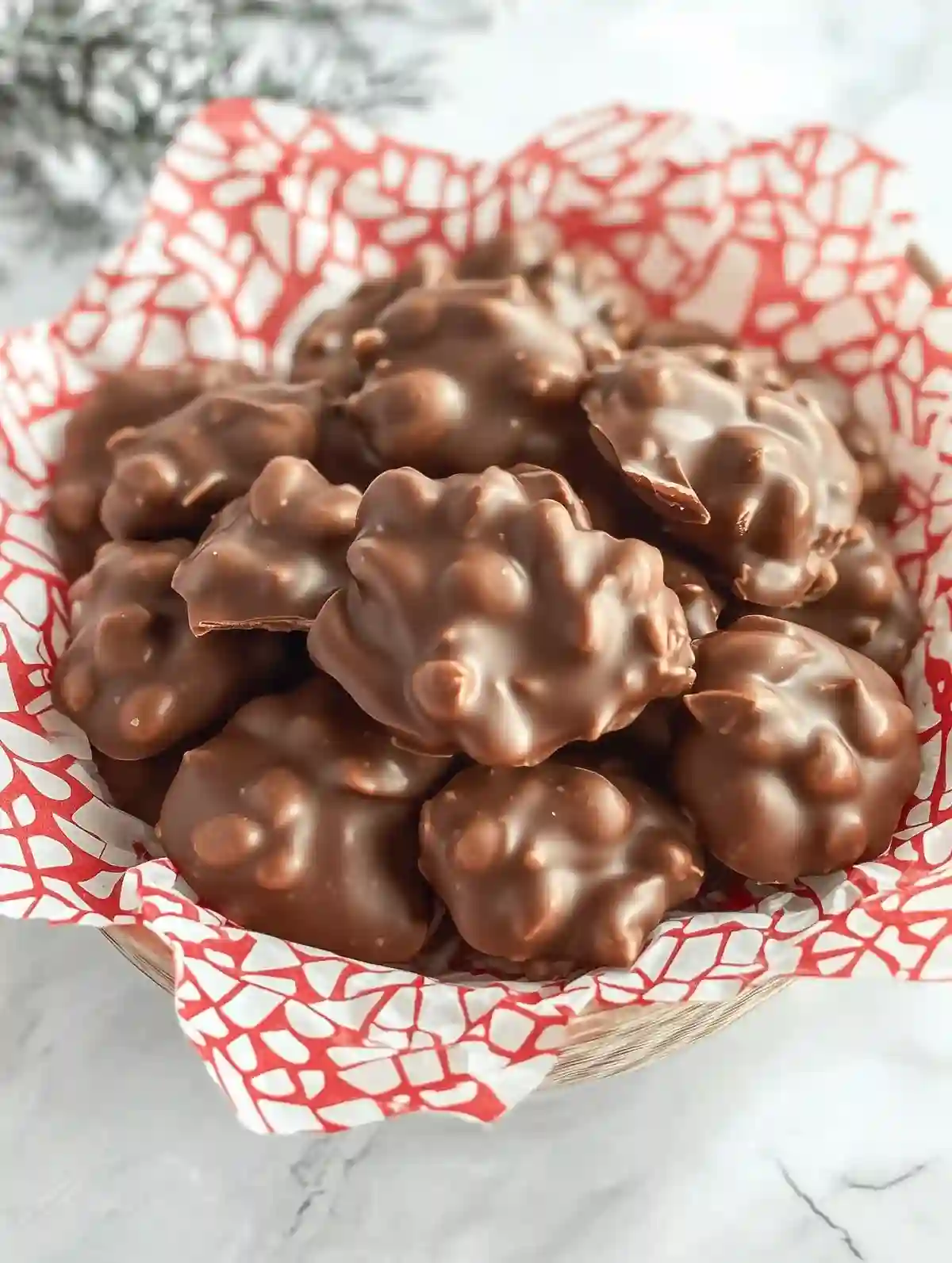 Chocolate peanut clusters in a decorative box on white marble surface