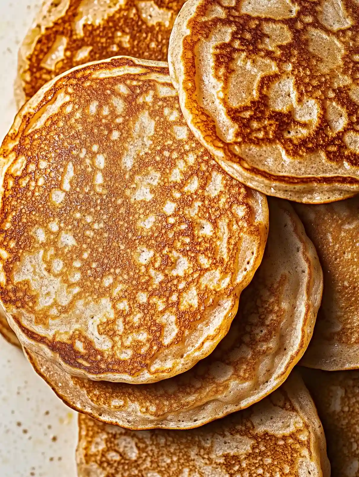 Stack of golden-brown einkorn pancakes on white marble surface
