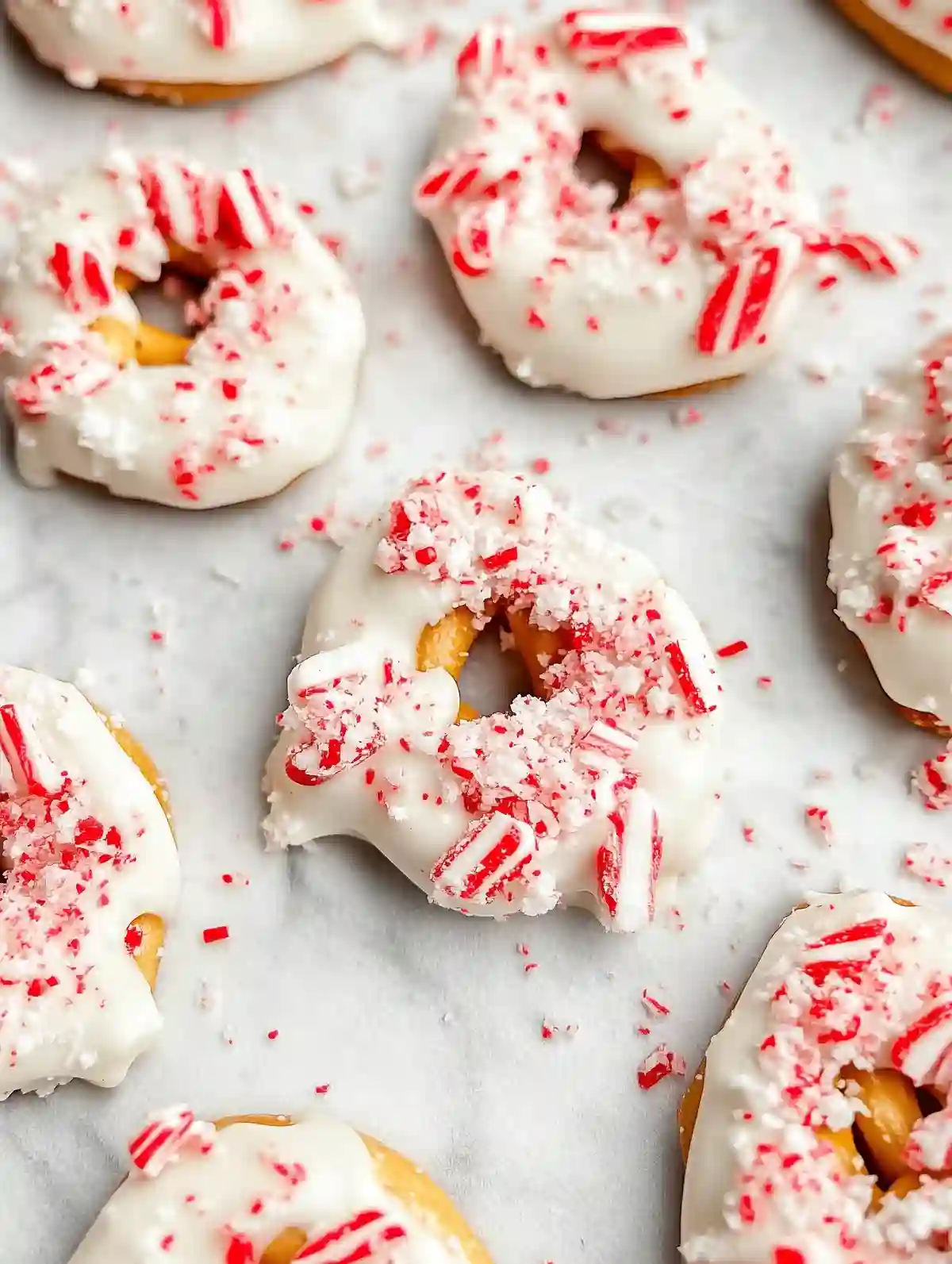 White chocolate-coated pretzels with peppermint bits on marble surface