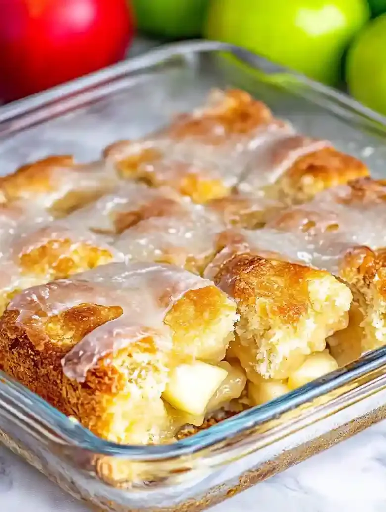 Baked apple pie biscuits in a square dish with golden crust and apple bits.