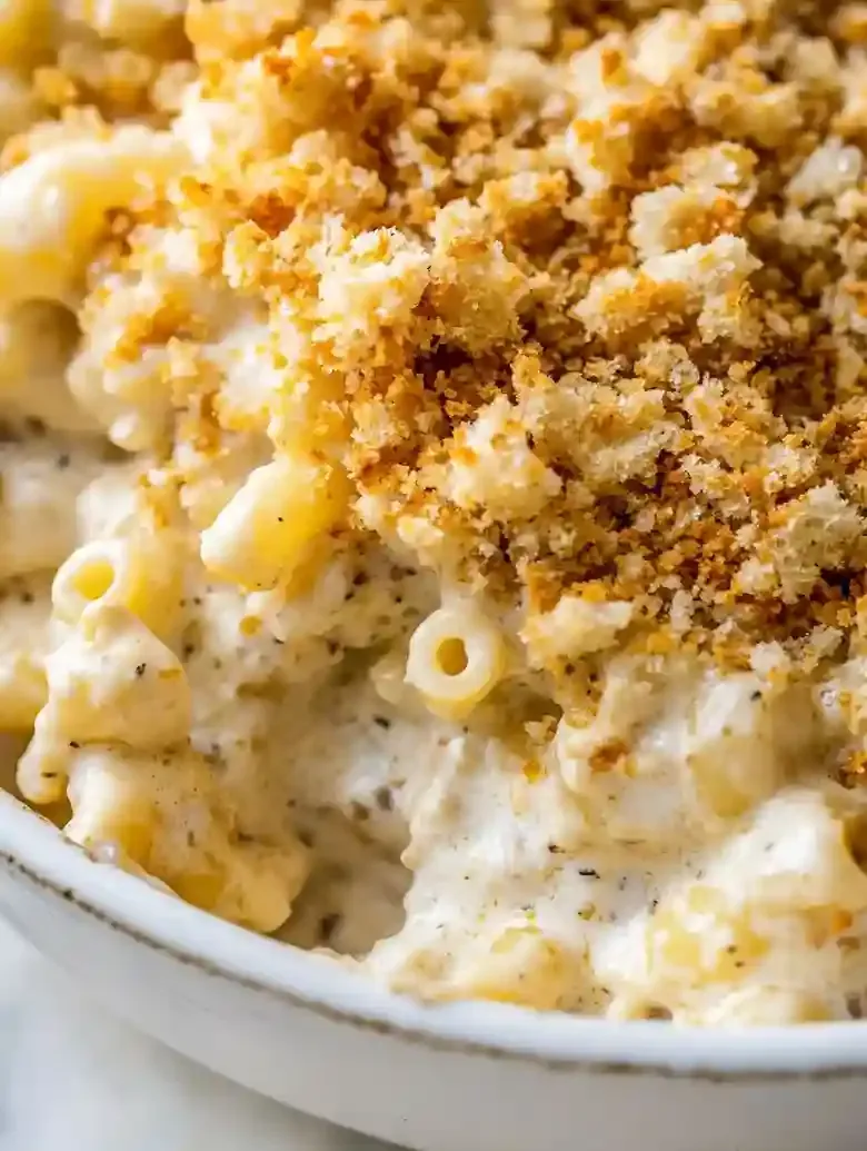 Macaroni and cheese topped with golden toasted breadcrumbs on marble surface.