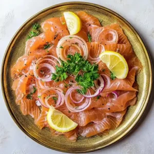 Sliced smoked salmon on a gold plate with parsley, onions, and lemon wedges.