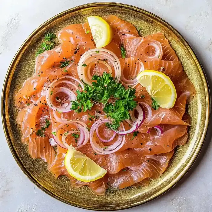 Sliced smoked salmon on a gold plate with parsley, onions, and lemon wedges.