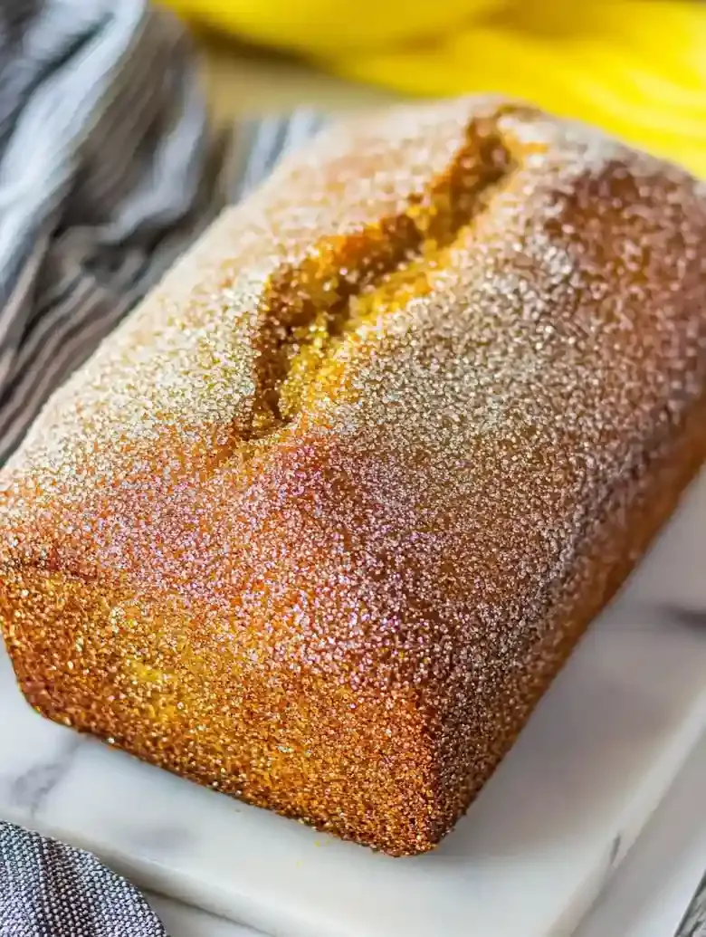 Cinnamon sugar donut loaf on white marble with gray veining.