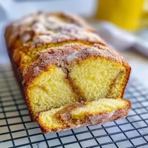 Cinnamon sugar donut bread loaf sliced on cooling rack, rustic setting.