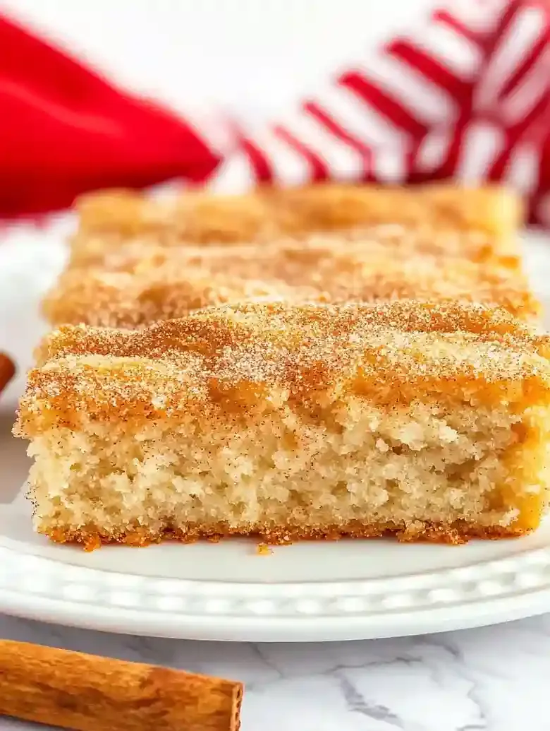 Cinnamon sugar biscuits on a decorative plate, with a cinnamon stick nearby.