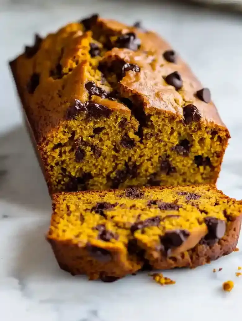 Dark chocolate pumpkin bread loaf with chocolate chips on marble surface.