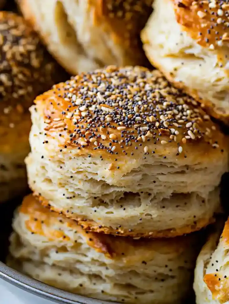 Stacked everything bagel swim biscuits in a baking dish on marble surface.