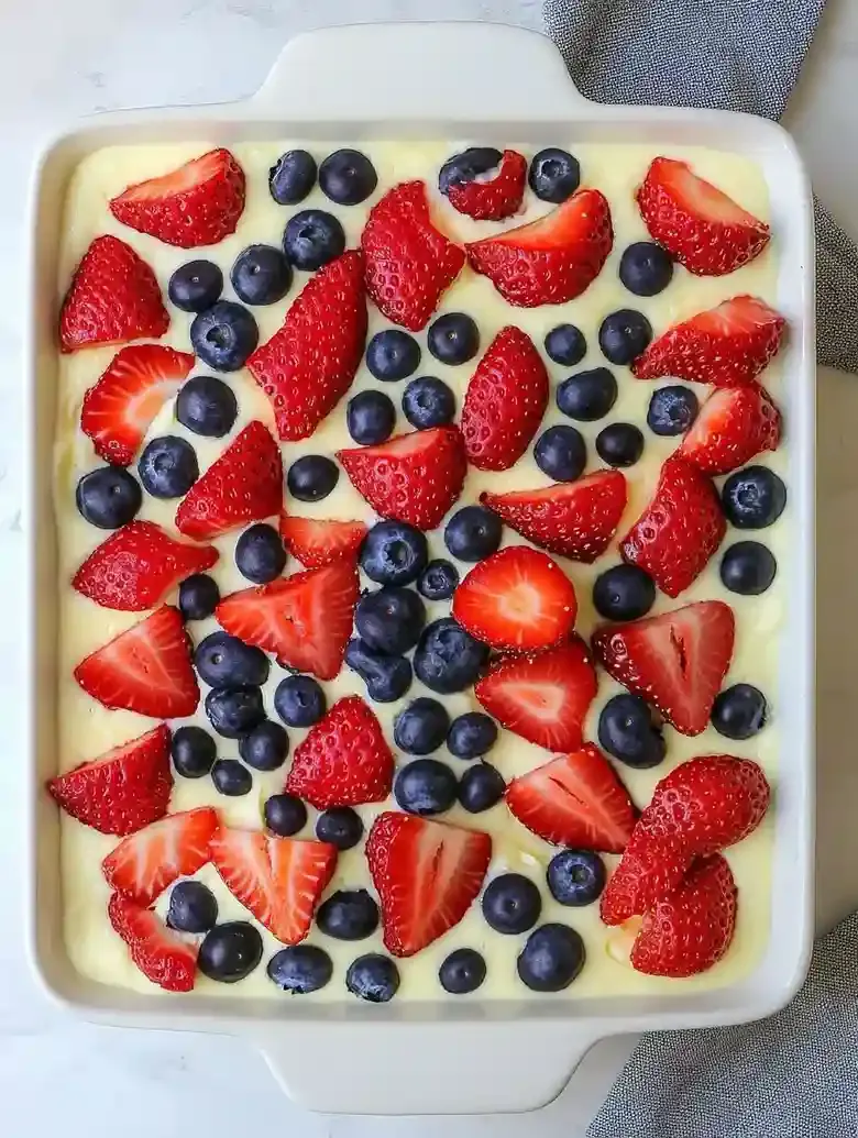 Rectangular dessert dish with strawberries and blueberries on a marble surface.
