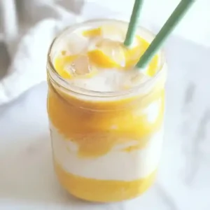Turmeric iced latte in a jar with ice and two reusable straws.