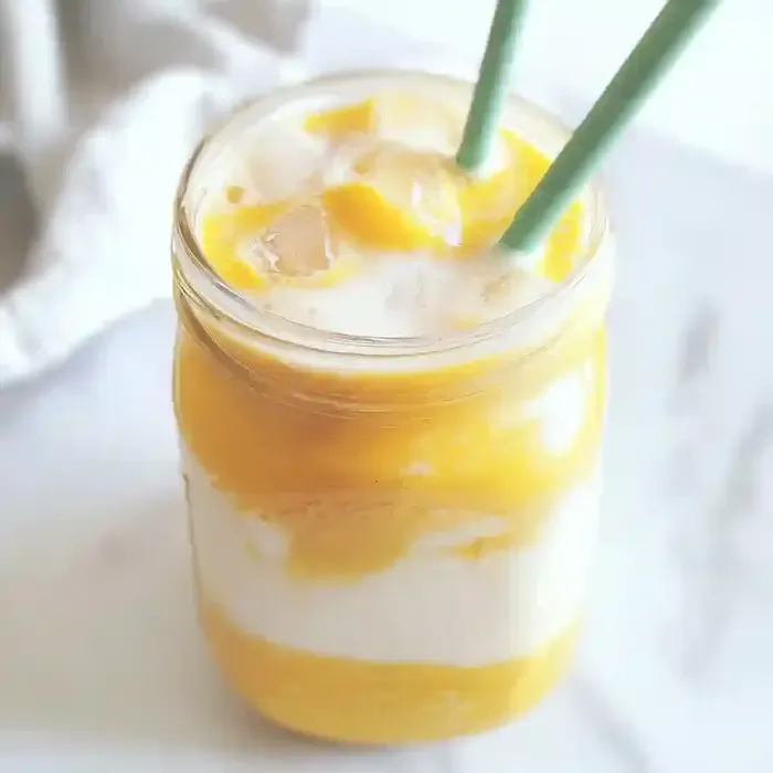 Turmeric iced latte in a jar with ice and two reusable straws.