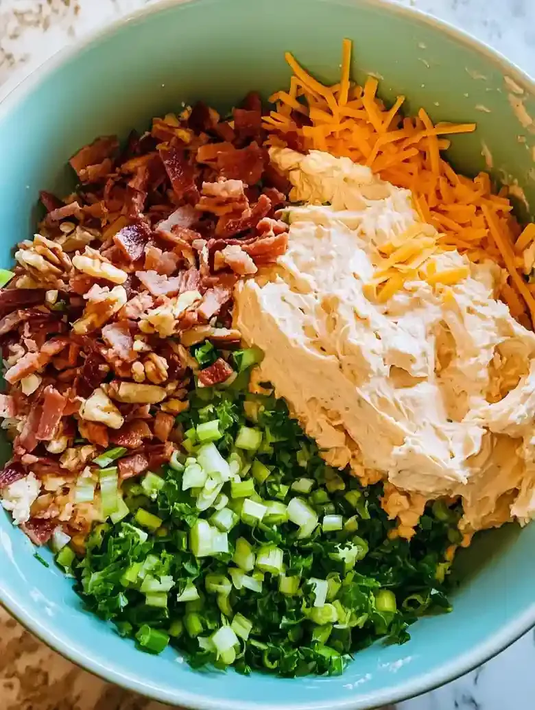 Light blue bowl filled with cream cheese, bacon, green onions, and cheese.