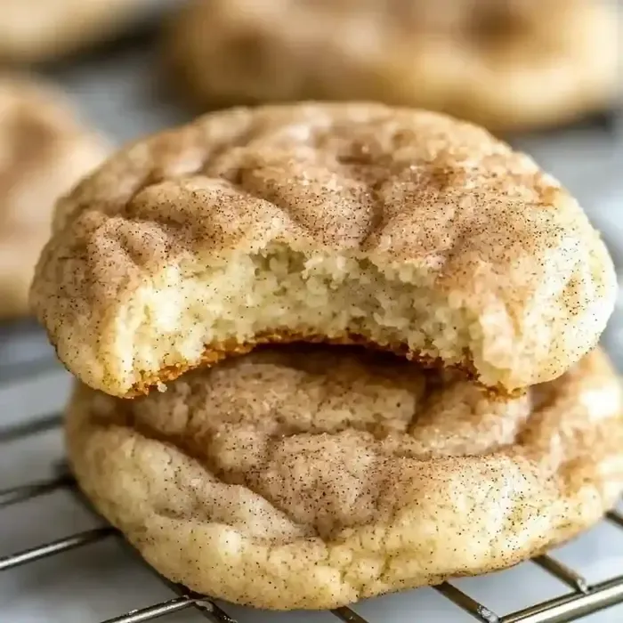 Two cream cheese snickerdoodles, one bitten, on a marble background.